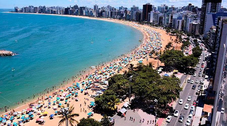 orla da praia da costa no verão com mar e céu azuis lotada de banhistas